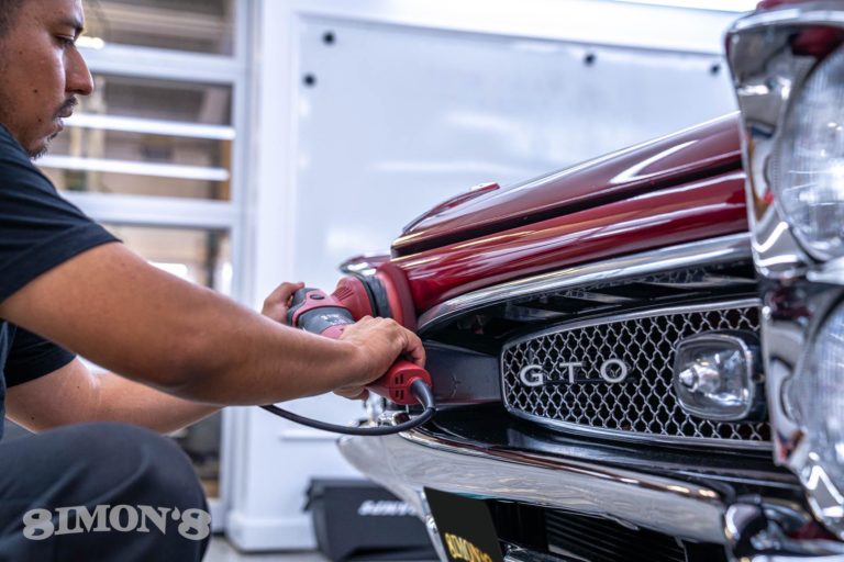 Detailing polishing the front clip of a 1967 Candy Apple Red Pontiac GTO.