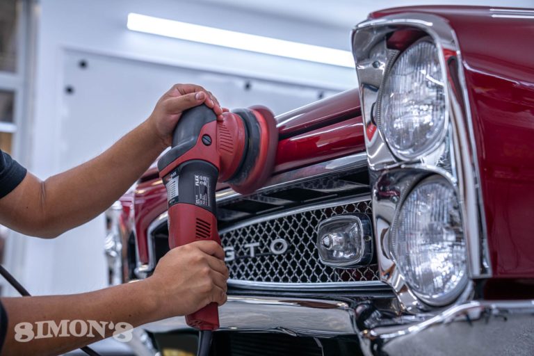 Detailer polishing a 1967 Candy Apple Red Pontiac GTO.