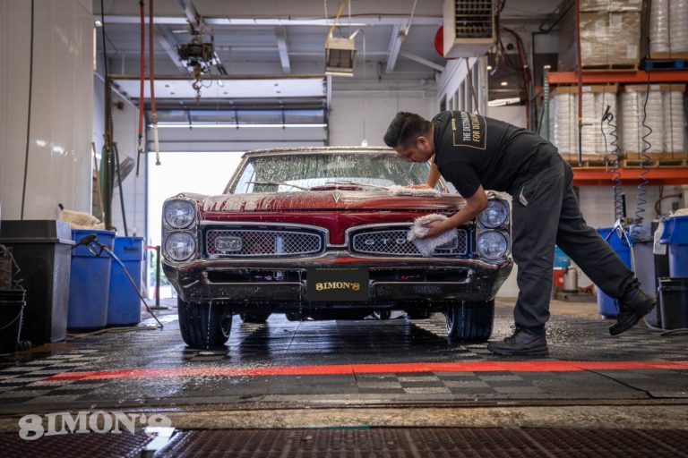 Detailer washing the grill of a 1967 Candy Apple Red Pontiac GTO.