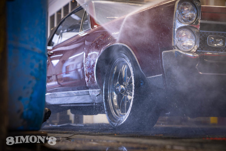 Pressure washing the fender on a 1967 Candy Apple Red Pontiac GTO.