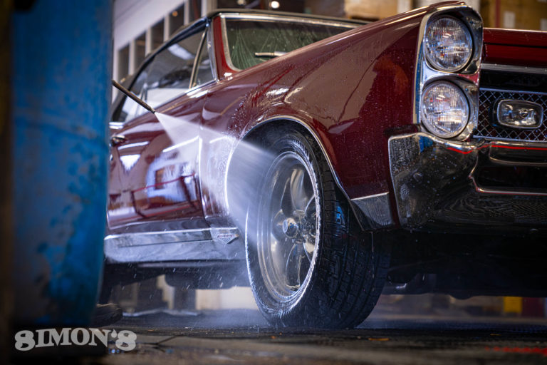 Pressure washing the wheels on a 1967 Candy Apple Red Pontiac GTO.