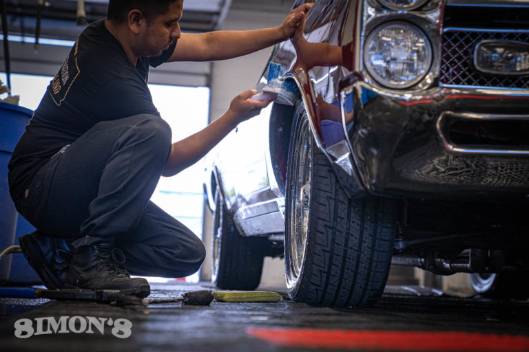 Cleaning the wheel wells of a 1967 Candy Apple Red Pontiac GTO.