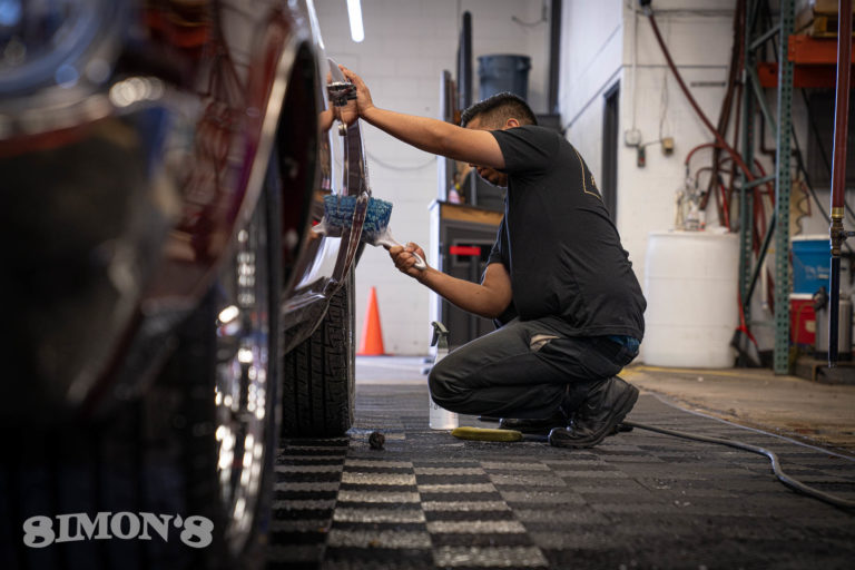Detailer brushing the wheel well of a 1967 Candy Apple Red Pontiac GTO.